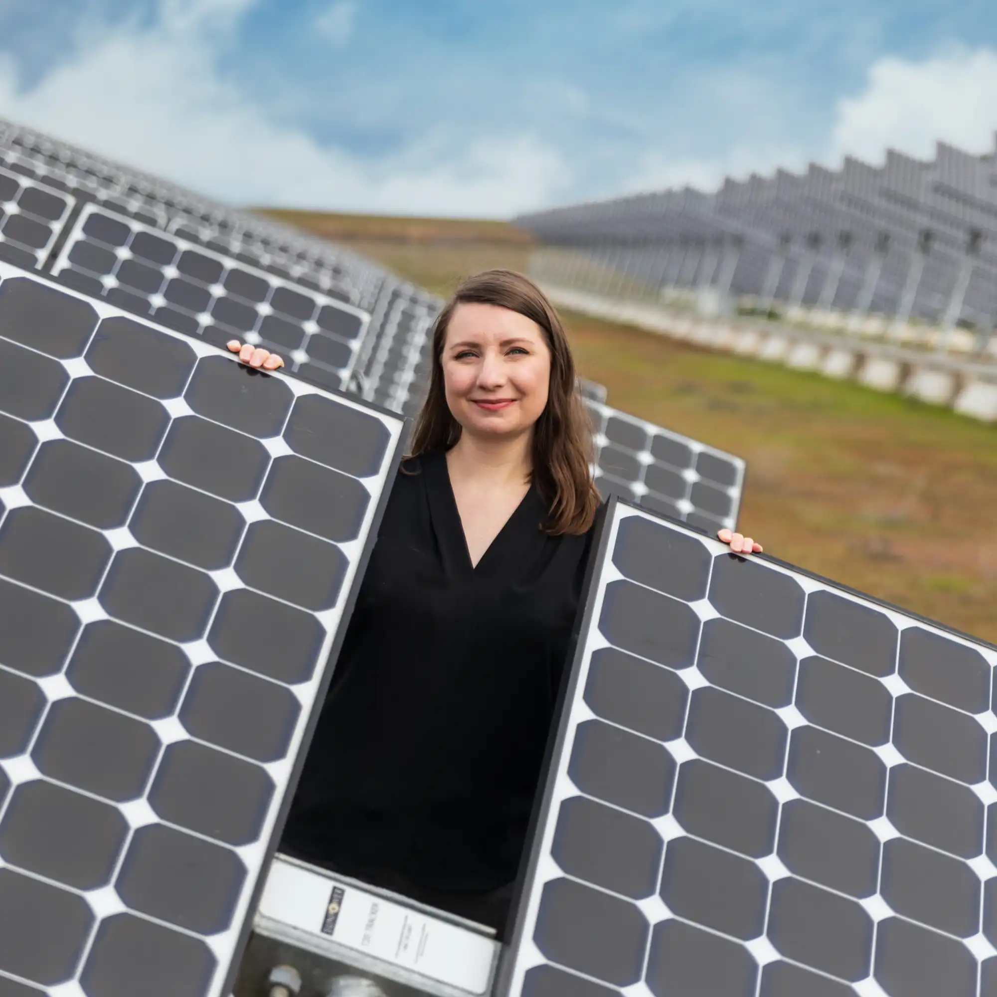 A UCM researcher standing behind solar panels in the UCM solar array.