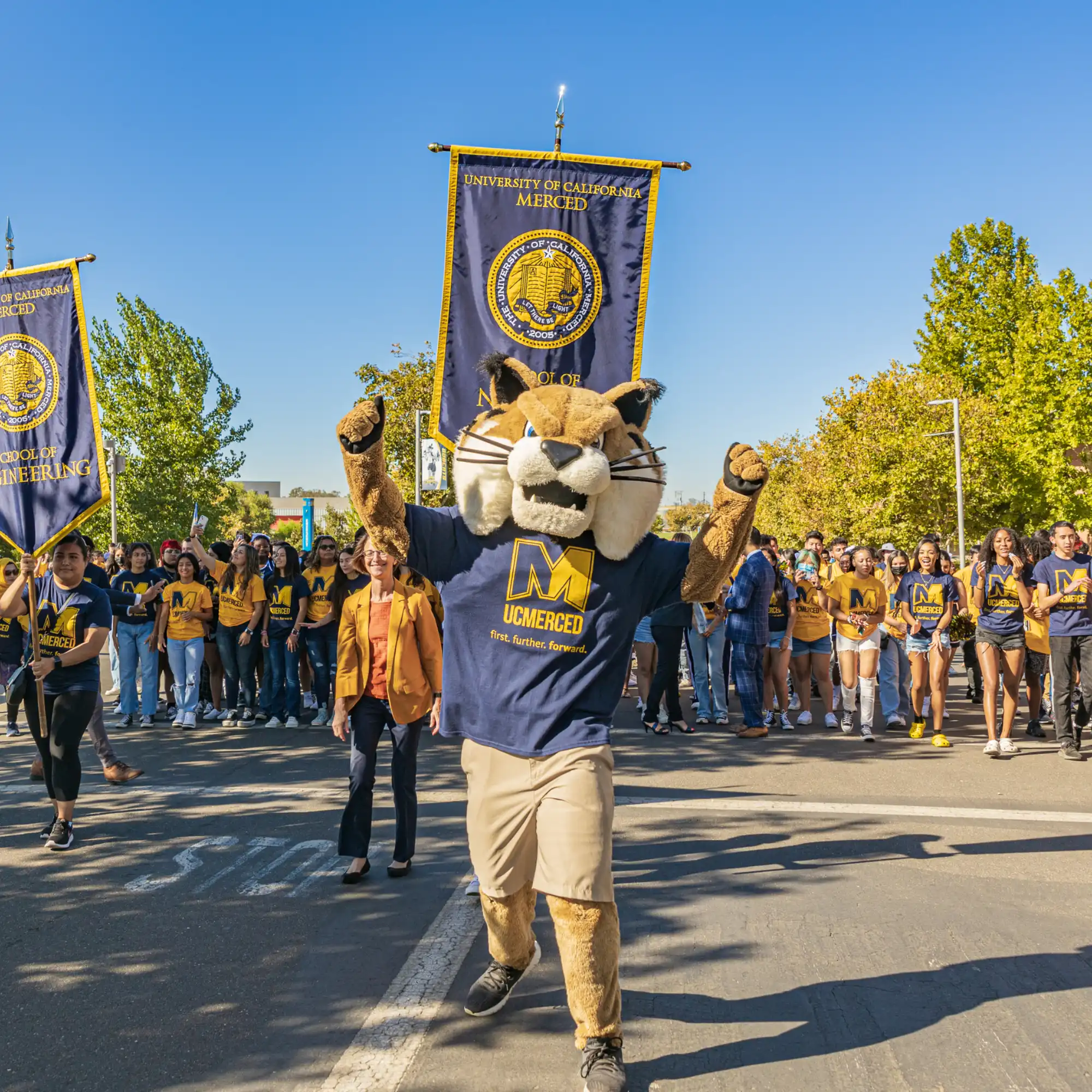 Rufus Bobcat and incoming freshman walking up Scholar’s Lane during the annual bridge crossing.